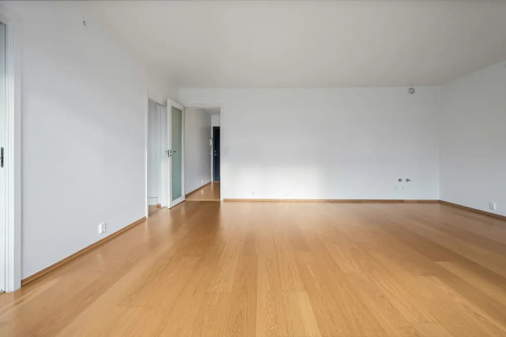 Pièce vide, plancher de bois clair et murs blancs