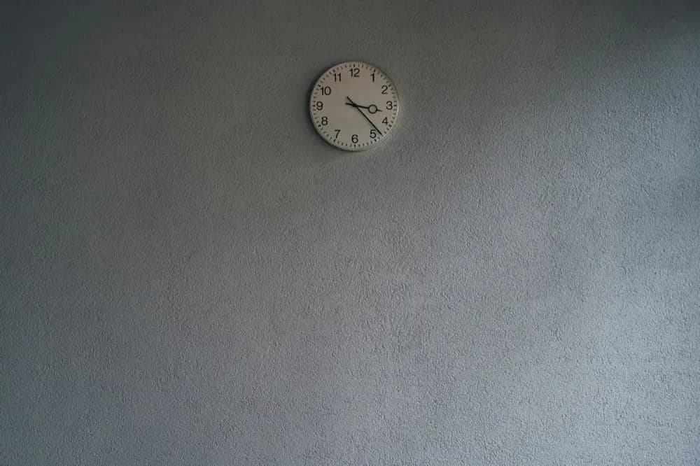 Horloge ronde accrochée haut sur un mur gris uni