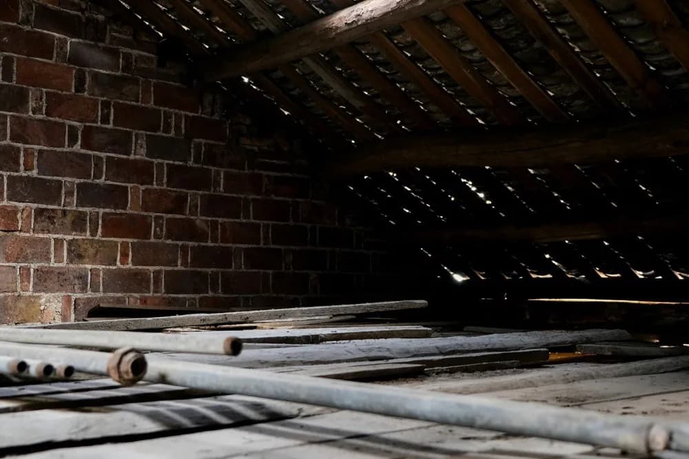 Plancher de comble poussiéreux devant un mur de brique
